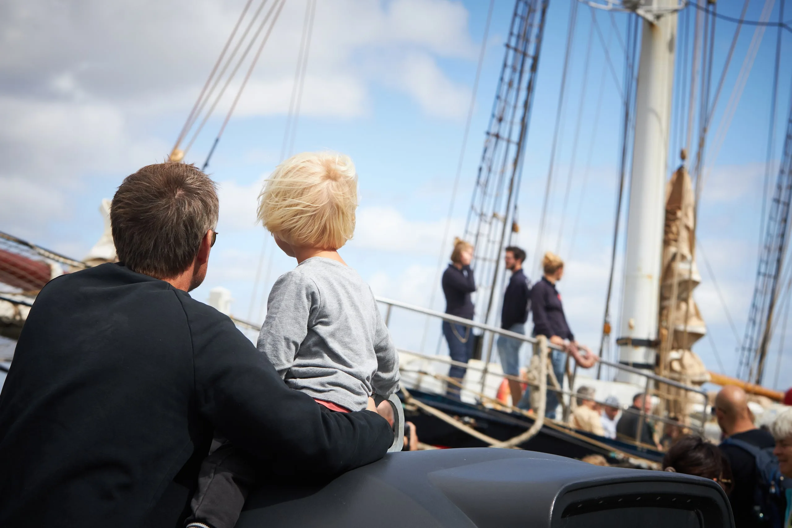 Padre e hijo mirando el horizonte desde la cubierta de un velero clásico